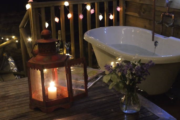 The outdoor bath tub at night time at the Hazel Tree Cabin in Buckinghamshire