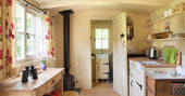 Interior of kitchen with wood burner and en suite bath room door open