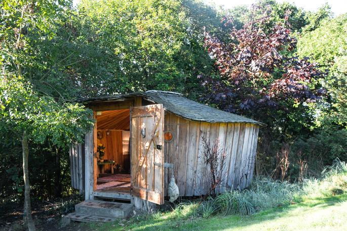 Pixie Yurt nestled in the tree’s with the front door open at Mill Valley in Cornwall