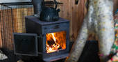 Roaring woodburner next to the bed inside of Pixie Yurt at Mill Valley