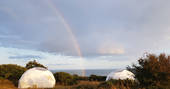 Two of the Geodomes with sea views and a rainbow at Wilderme in Cornwall