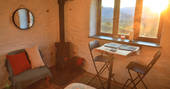 The Hog House bothy wood burner with sunshine coming in, Coniston, Cumbria