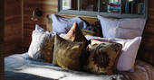 Relax in the cosy double bed at Netherby Treehouse, with its assortment of colourful cushions