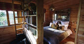 The comfortable and cosy double bed, and mezzanine accessed by a ladder inside Netherby Treehouse in Cumbria