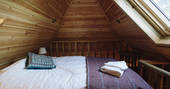 Comfortable twin beds tucked away in the cosy mezzanine accessed via a ladder inside Netherby Treehouse in Cumbria