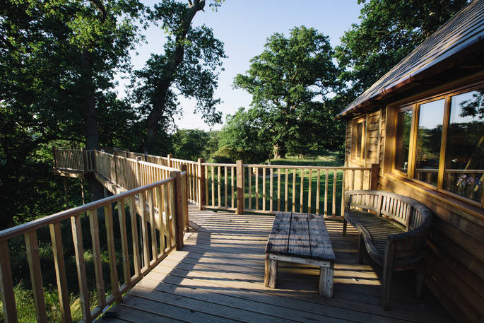 Admire the beautiful countryside scenery while you relax on the balcony with a glass of wine at Netherby Treehouse in Cumbria