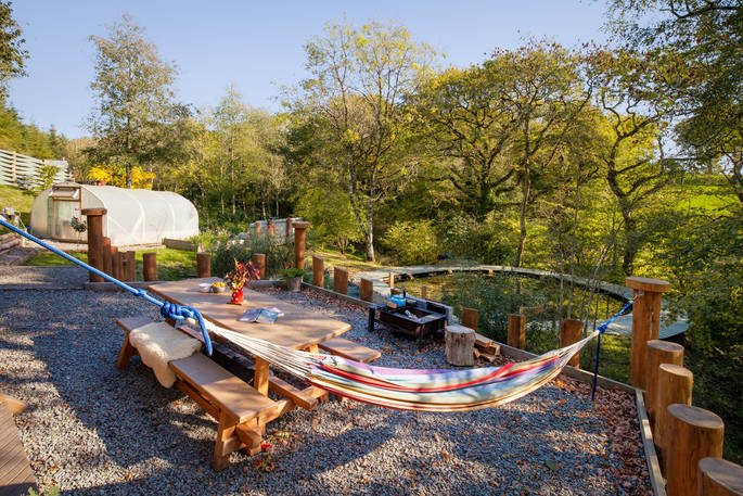 Relax on the hammock with amazing views of the Devon countryside outside Carpenter Cabin at Devon Dens