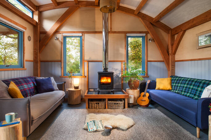 The cosy living room with a roaring log burner in Carpenter Cabin, Devon