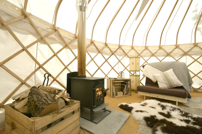 Sapperton Yurt interior with wood-burning stove and single futon bed