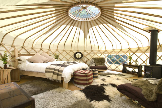 Interior of Yurt Reynolds with double bed and wood-burner at Westley Farm in Gloucestershire 