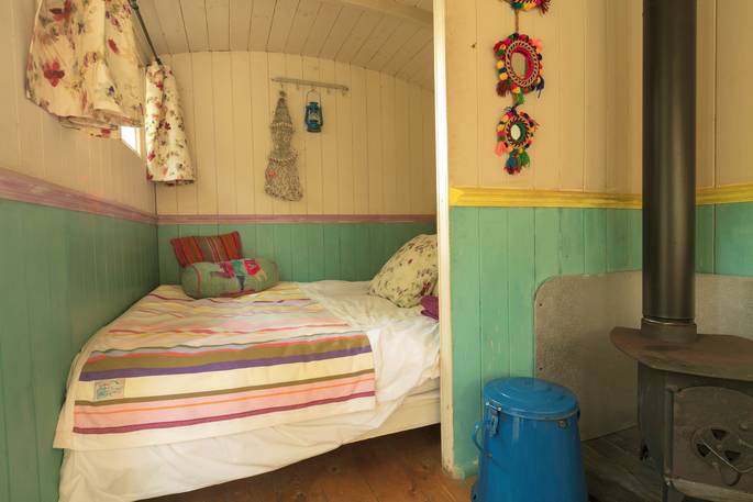 The cosy double bed, tucked in the corner at Lima Shepherd's Hut in Gloucestershire