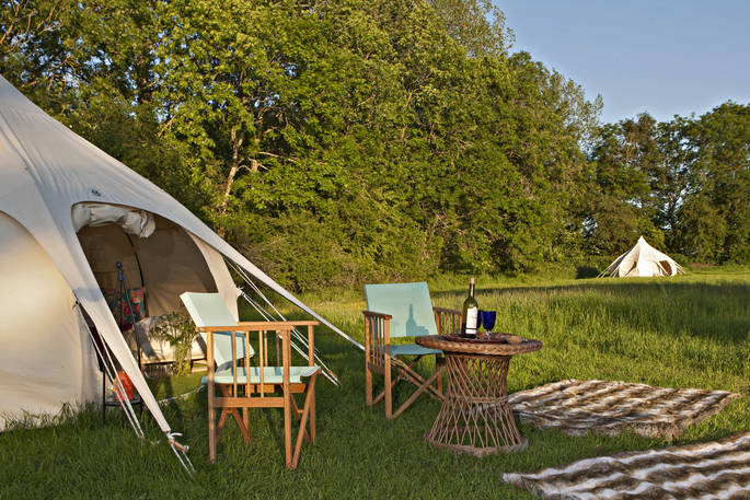 Sit outside your bell tent in the evening sun with a glass of wine at Wild Wood Bluebell in Gloucestershire