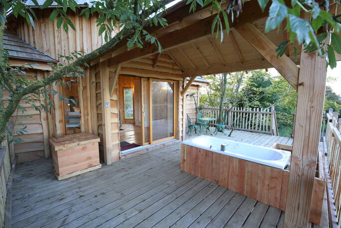 Relax in the outdoor jacuzzi bath on the decking outside of the lodge treehouse
