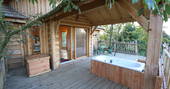 Relax in the outdoor jacuzzi bath on the decking outside of the lodge treehouse