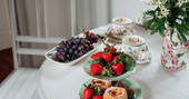 Delicious afternoon tea with strawberries and grapes is laid out on a pretty vintage tea set inside Sergeant Troy