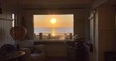 The Beach House cabin interior view of the sea and sunset, Isle of Sheppey, Kent, England