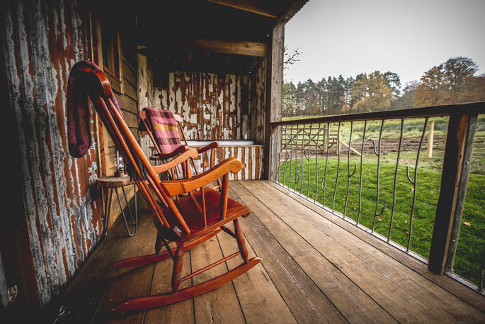 View from Rowan cabin's outside decking. Admire the greenery of Hesleyside Huts in Northumberland from the rocking chairs next to the outdoor bath