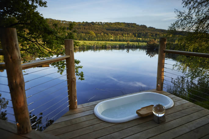 Outdoor bath tub with scenic view to the pond