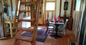 Jacaranda Cabin interior living space with ladder leading up to mezzanine level with double bed