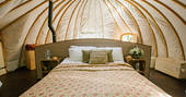 The comfortable kingsize bed inside The Slades tent at Penhein Glamping in Monmouthshire