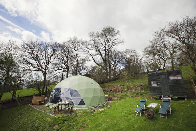Exterior shot of The Dome in Powys Wales featuring sunbeds and a hot tub