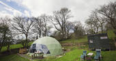 Exterior shot of The Dome in Powys Wales featuring sunbeds and a hot tub