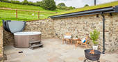 Hot tub and fire pit in the outdoor space next to The Burrow at Dolassey Farm in Powys