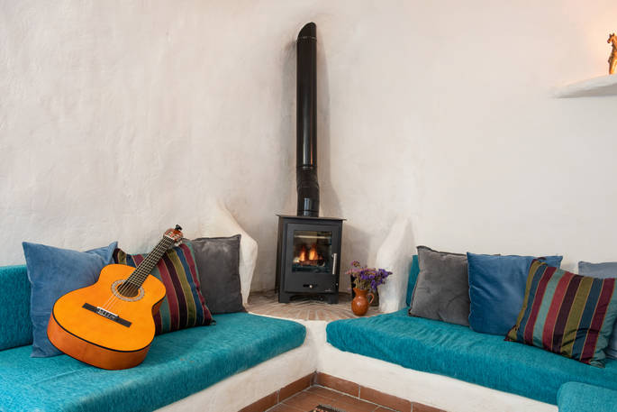 Seating area with guitar and wood burner at Casa Isadora Cave House, Almeria, Spain