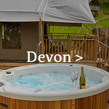 Wine glasses sit on the edge of the hot tub at Brownscombe safari tent in Devon